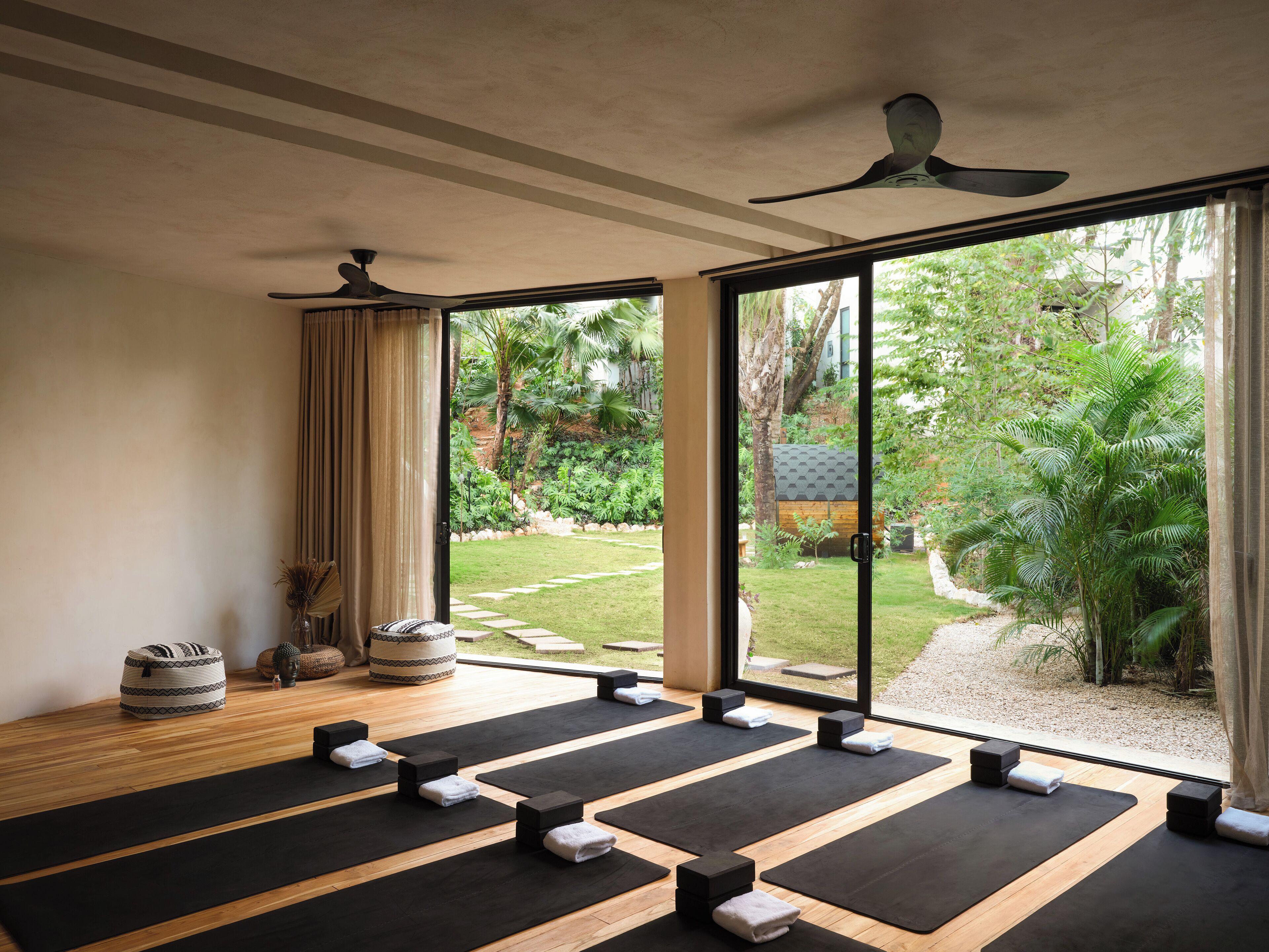 A yoga room with mats, blocks, and a view of a garden.