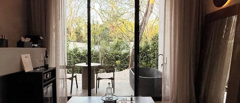 Una habitación moderna con sofá, una mesa y vista a un jardín a través de amplios ventanales correderas.