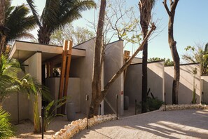 A modern building with a minimalist design, surrounded by palm trees and a gravel pathway. - Esh Hotel and Spa, a Member of Design Hotels (Nosara)