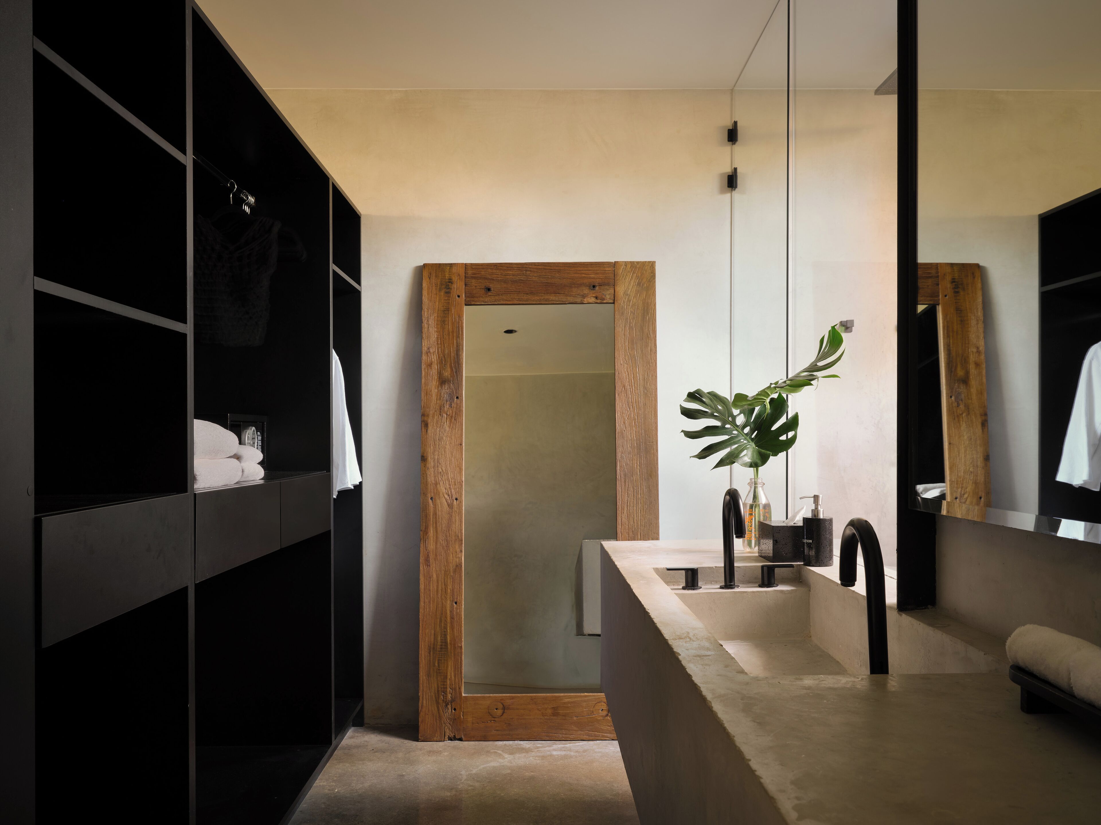A modern bathroom with a wooden vanity, a large mirror, and a plant.