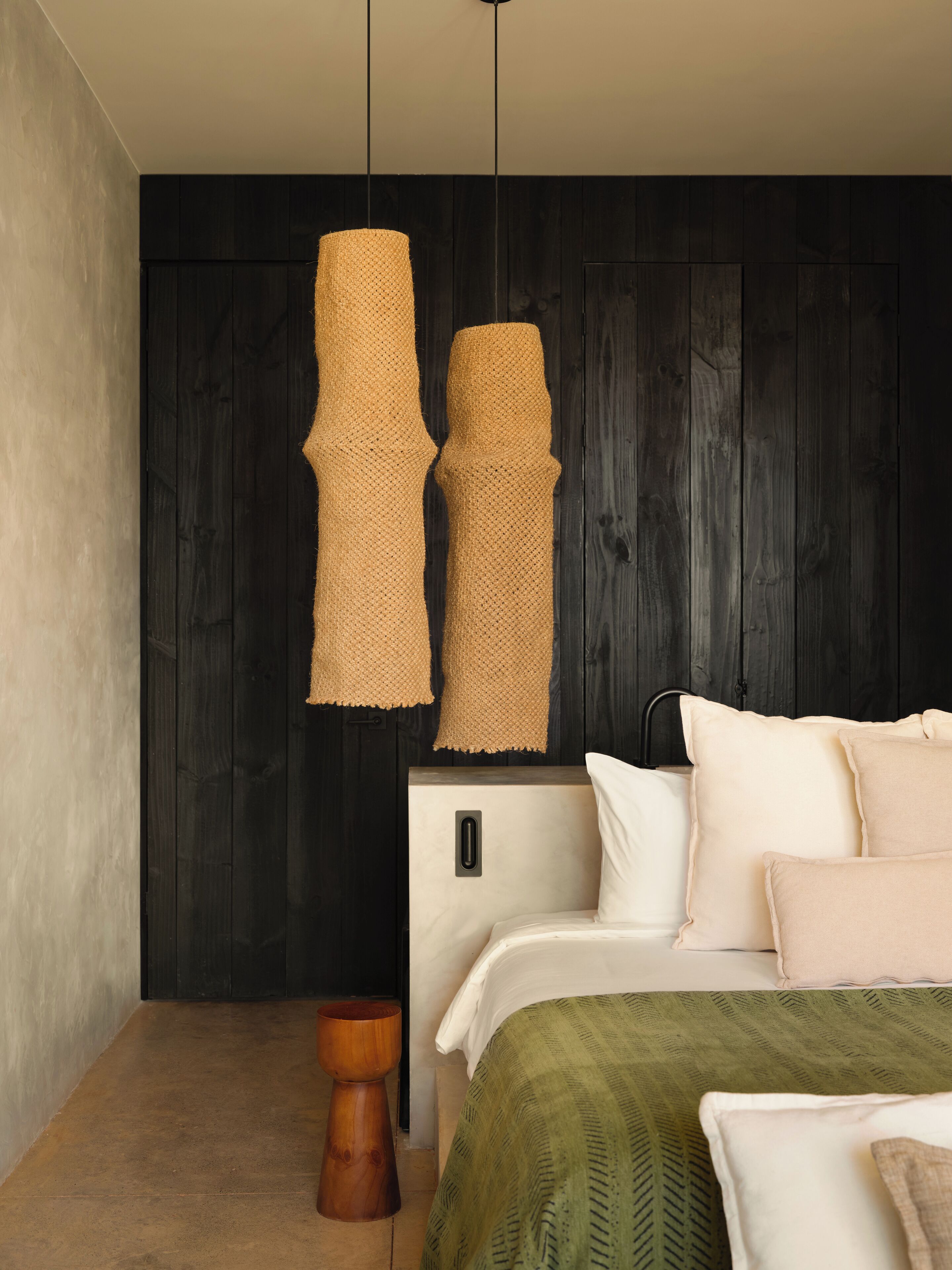 A bedroom with a bed, a bedside table, and a hanging light fixture.