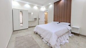 Een moderne slaapkamer met een groot bed, een garderobe, een spiegel en een wand van hout.