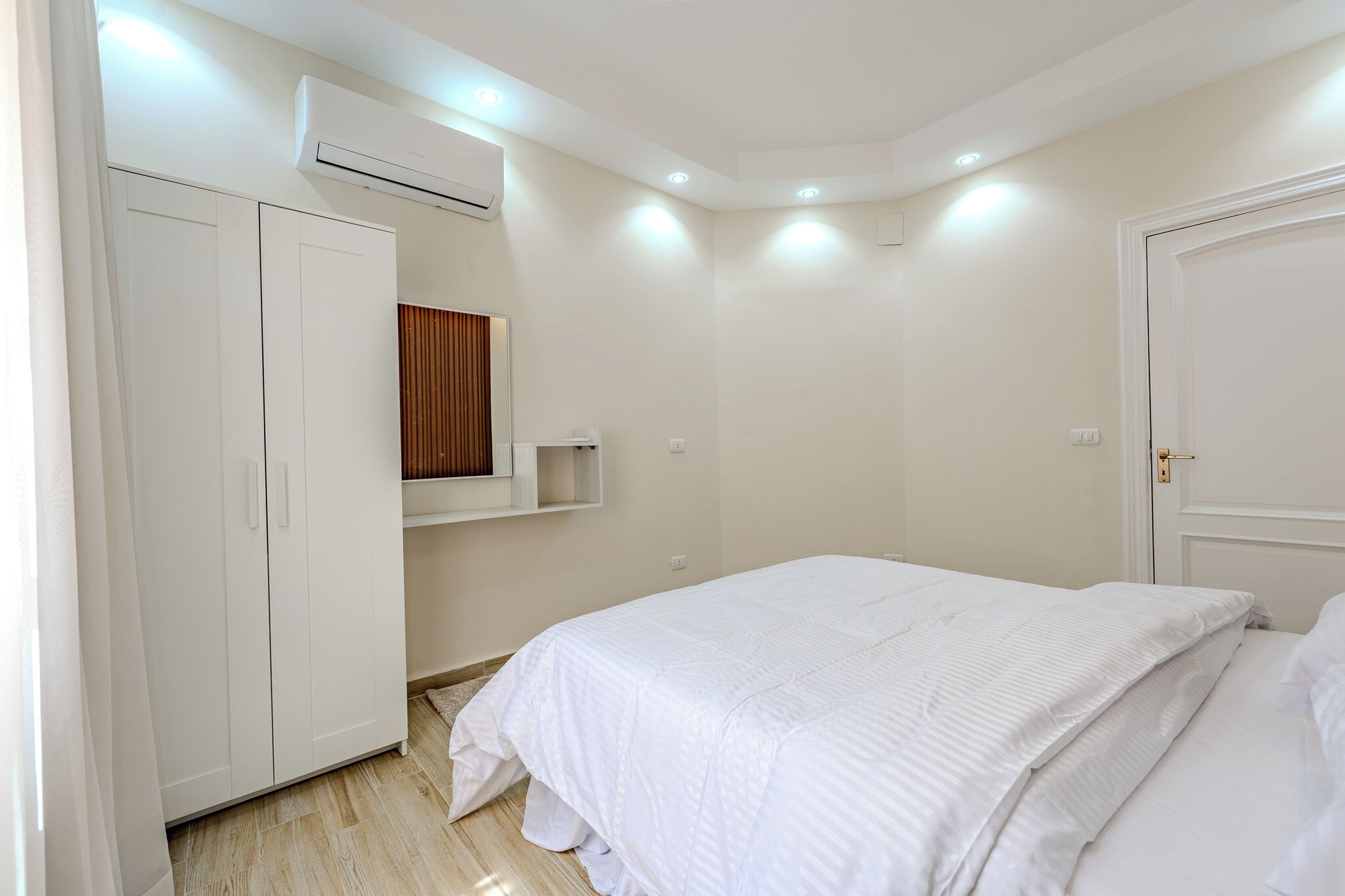 A bedroom with a bed, wardrobe, and built-in shelf.