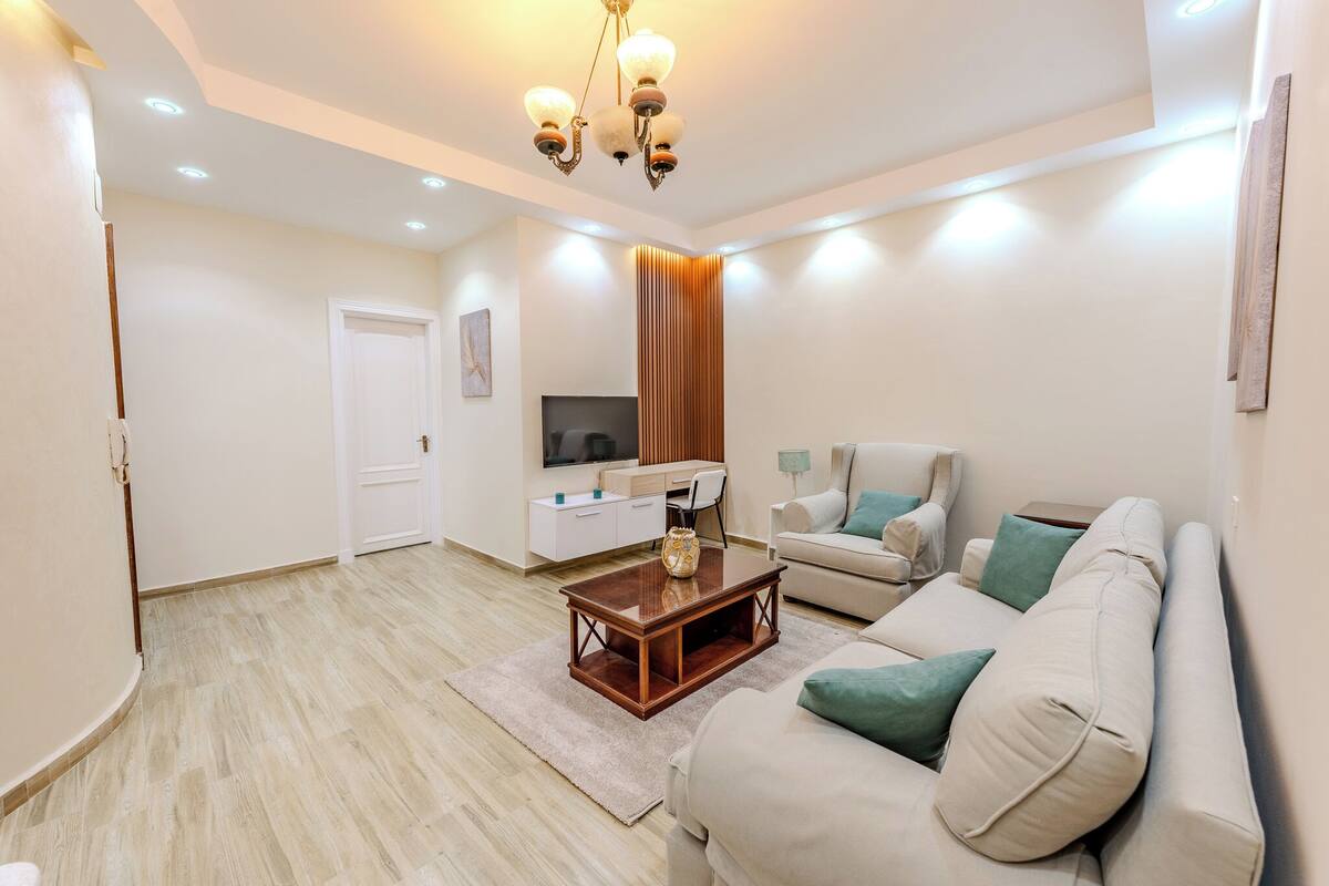 A modern living room with a sofa, a coffee table, a TV, and a wooden partition.