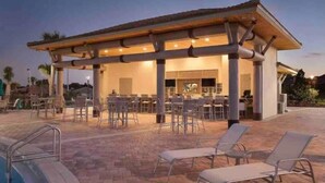 A covered outdoor area with a pool, lounge chairs, and a bar. - Champions Gate Resort Townhome with Private Pool (Davenport)