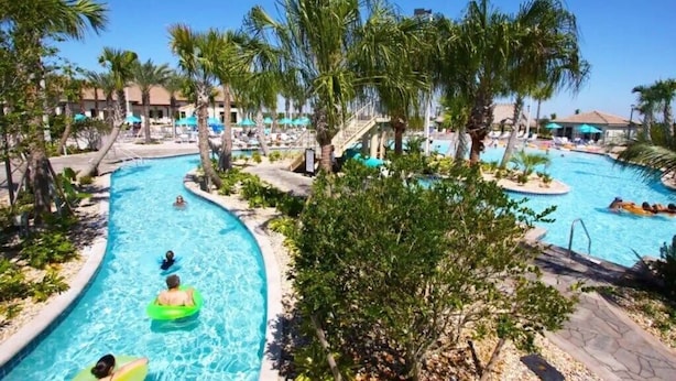 A pool area with multiple swimming pools, palm trees, and lounge chairs. - Champions Gate Resort Townhome with Private Pool (Davenport)