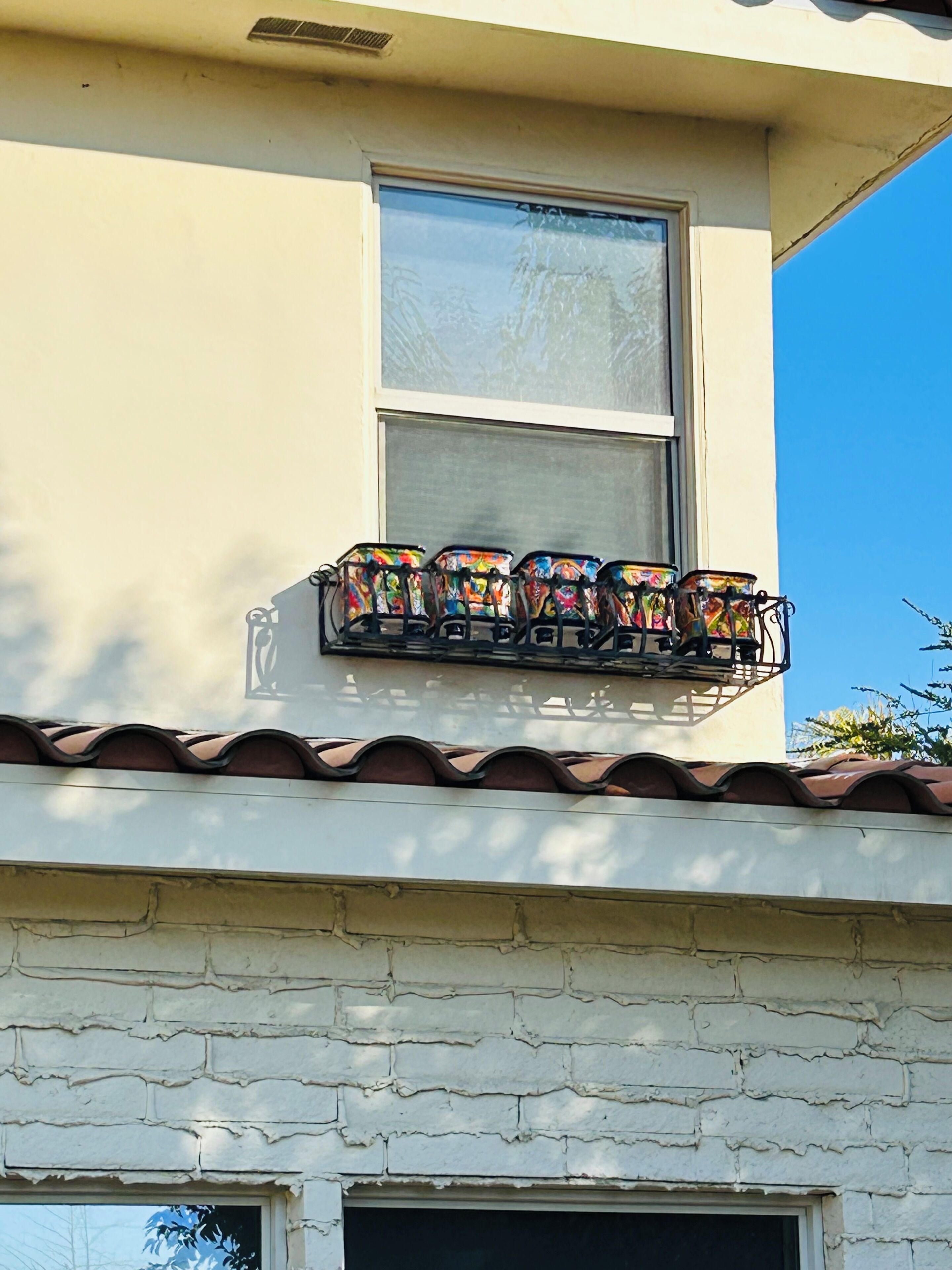 A building with a window and a balcony with colorful chairs.