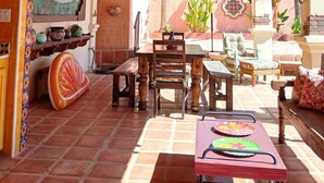 Un interior rústico con vigas de madera, un ventilador de techo y un comedor con mesa y sillas.