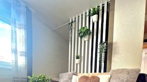 Un salon moderne avec une table basse en bois, un tapis gris, un canapé violet agrémenté de coussins décoratifs et un mur végétal vertical.