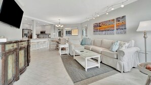A spacious living area with a sofa, coffee table, and a TV mounted on the wall. - Bay View CLOSE to Beach, Shops, Restaurants, Marina (Bradenton Beach)