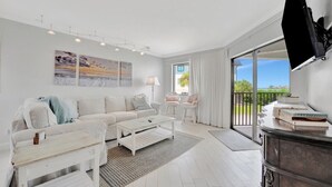 A modern living room with a white sofa, coffee table, and a flat-screen TV mounted on the wall. - Bay View CLOSE to Beach, Shops, Restaurants, Marina (Bradenton Beach)