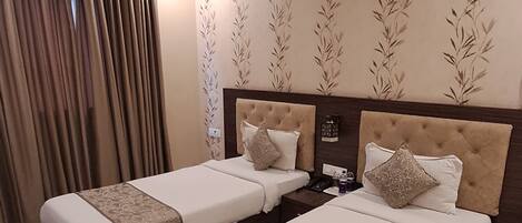 A hotel room with two beds, a ceiling fan, and a large window with curtains.