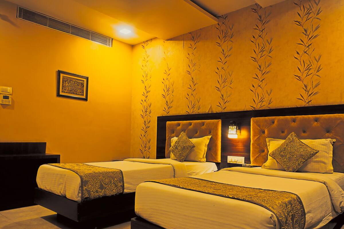 Quarto de hotel com duas camas, uma janela grande e ar condicionado fixado na parede.