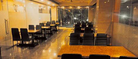 A restaurant with tables and chairs arranged in rows, large windows, and a modern interior design.