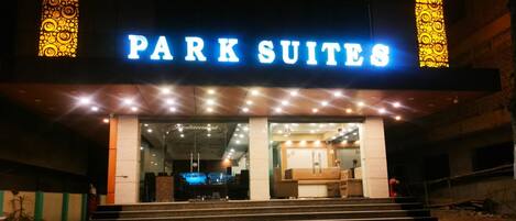 L’entrée d’un hôtel, avec une enseigne indiquant « PARK SUITES », et un espace de réception visible à travers les portes vitrées.