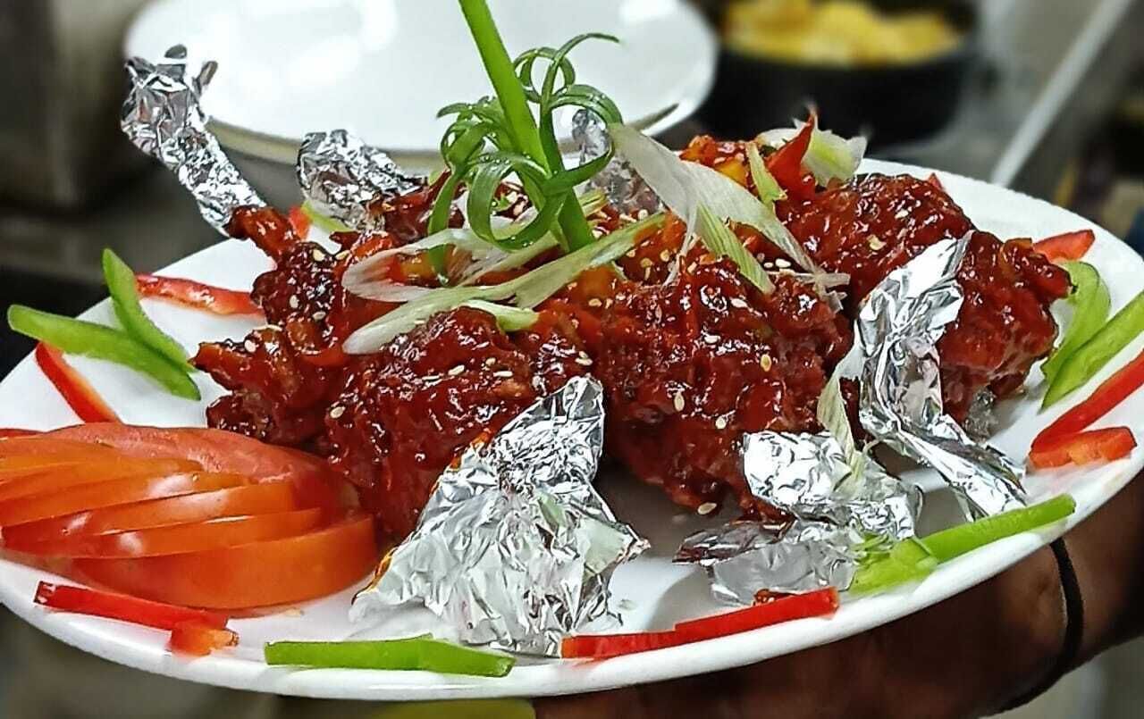 A plate of food with foil-wrapped items, garnished with green onions and red peppers.