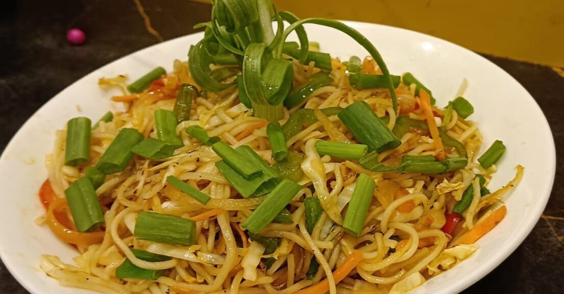 A plate of stir-fried noodles with vegetables.