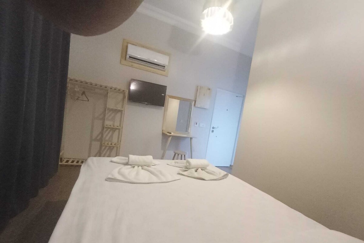 Une chambre d’hôtel avec un lit, un téléviseur fixé au mur, une armoire et une porte.