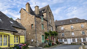 A stone building with a traditional design, featuring multiple windows and a visible staircase leading to the entrance.