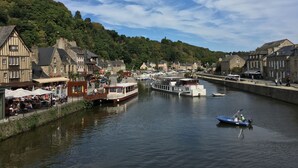 A riverside town with historic buildings, a boat docked at the pier, and a small boat on the water.