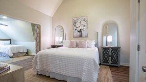 Une chambre à coucher avec un grand lit, deux tables de chevet, une commode et un miroir.
