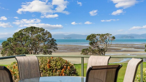 Una terraza con mesa y sillas con vista a una playa y al mar.