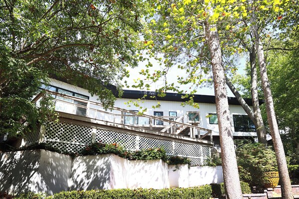 Un edificio moderno con fachada blanca, múltiples ventanas y una escalera de madera que lleva a un balcón.