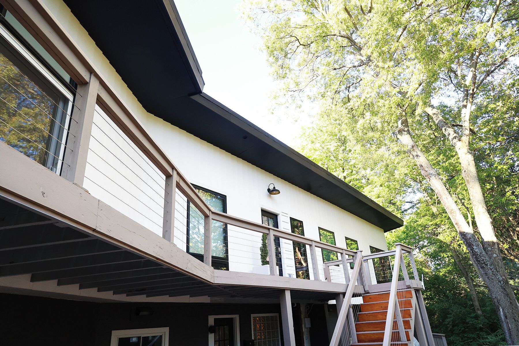 Un bâtiment moderne doté d’un toit plat, de grandes fenêtres et d’un balcon avec une rambarde en métal.