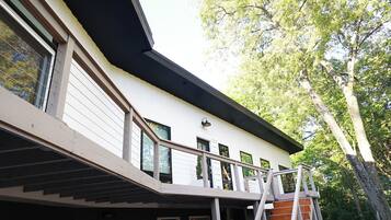 Un bâtiment moderne doté d’un toit plat, de grandes fenêtres et d’un balcon avec une rambarde en métal.