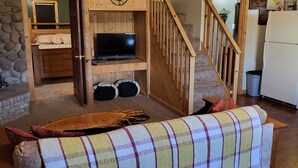 Un accogliente soggiorno con una scala in legno, un camino e un televisore.