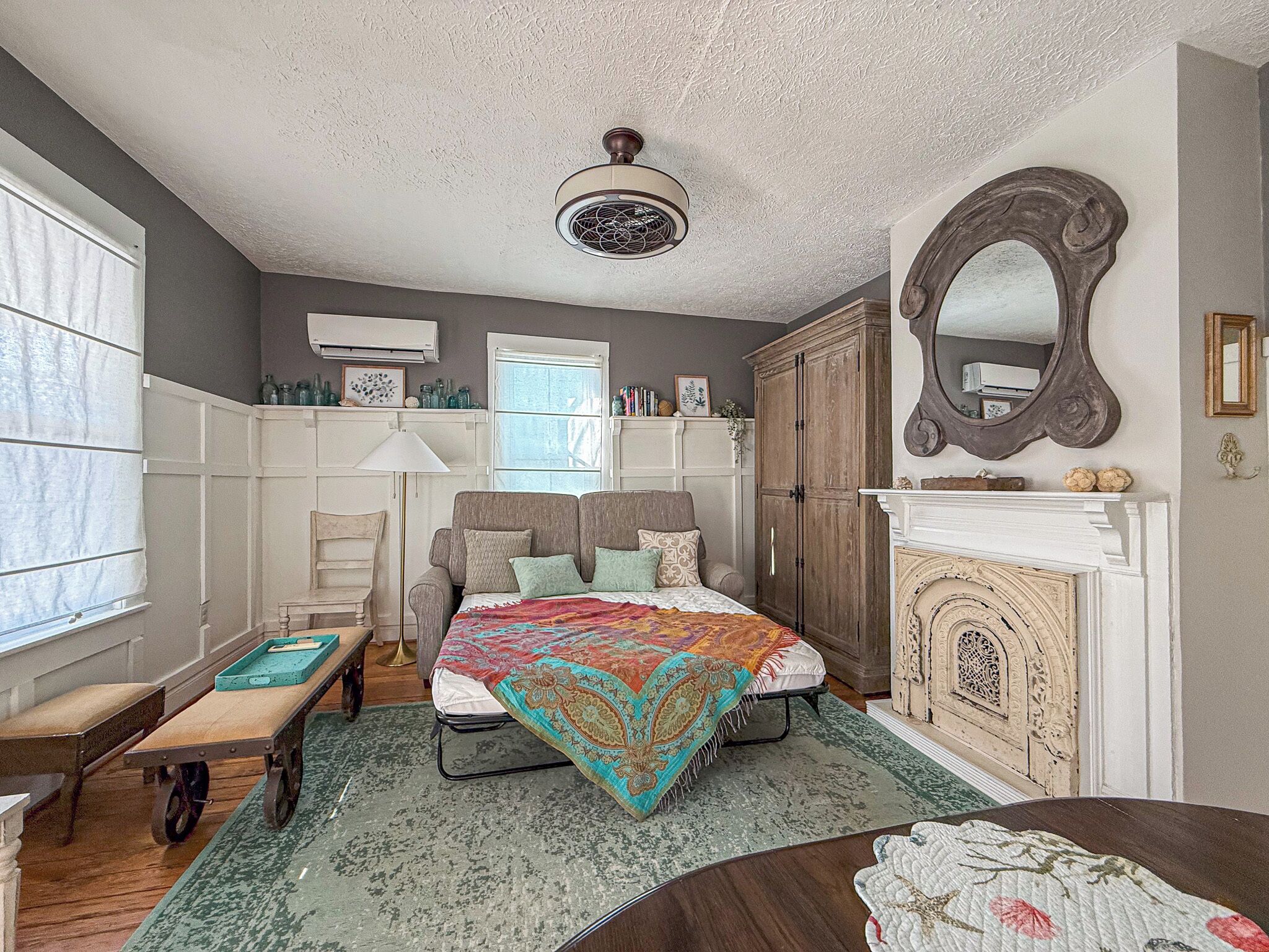 A bedroom with a bed, a dresser, a mirror, and a window.