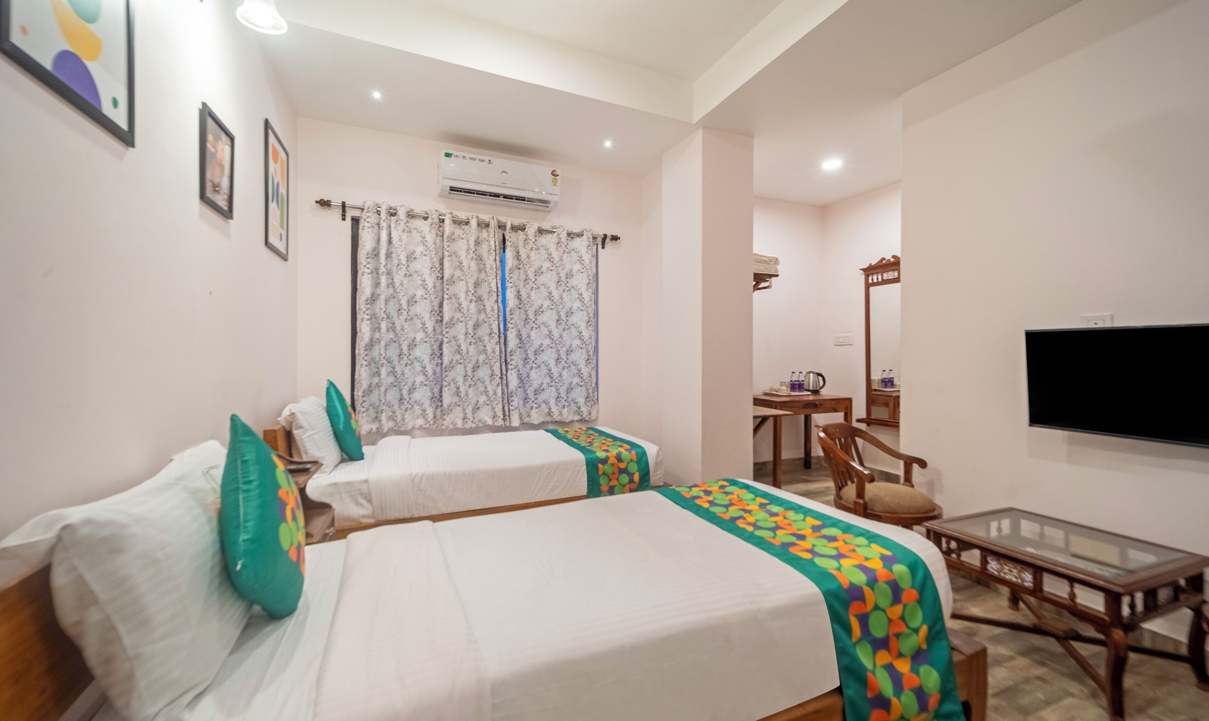 A hotel room with two beds, a TV, a desk, and a chair.