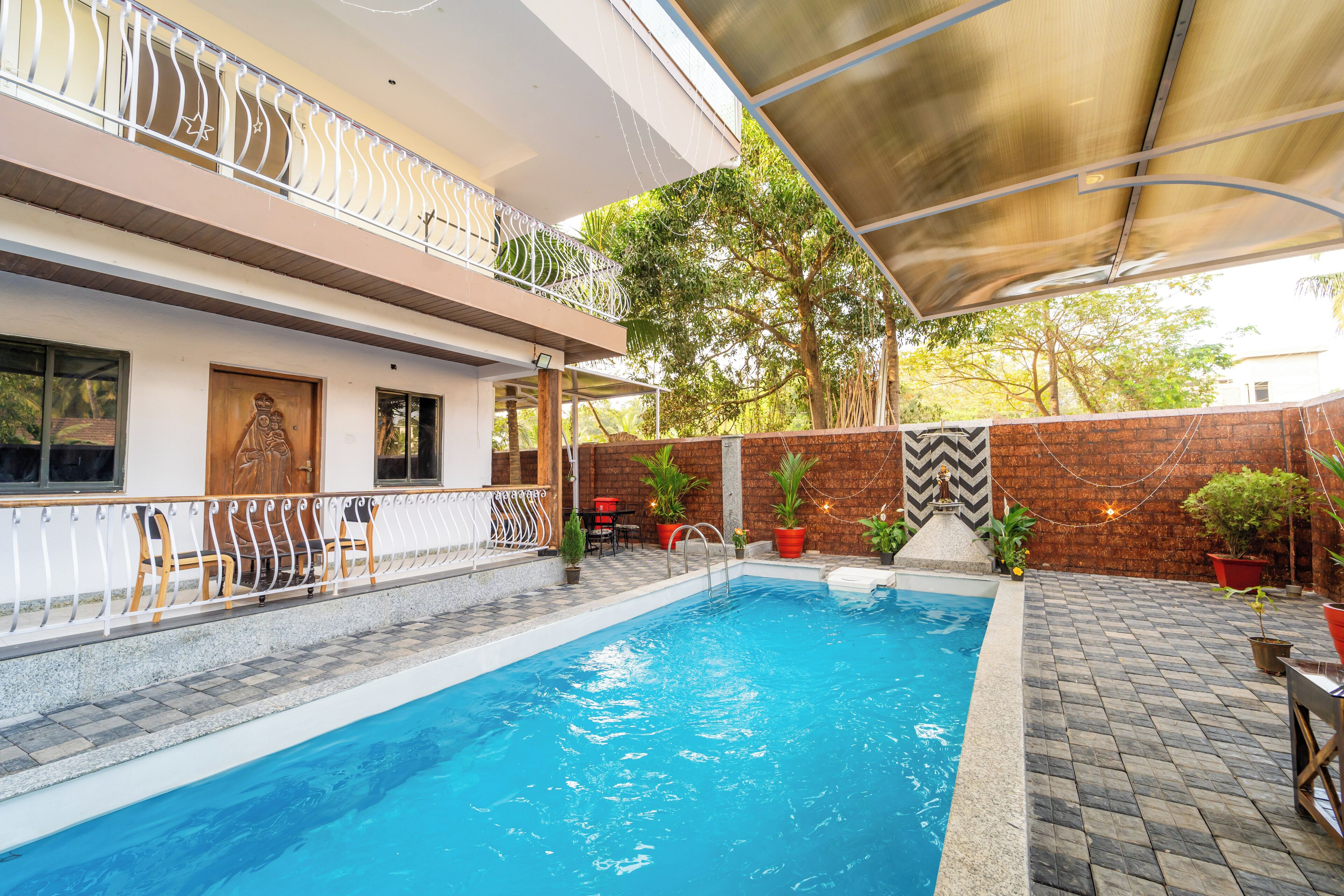 A swimming pool with a covered area, a wooden door, and potted plants.