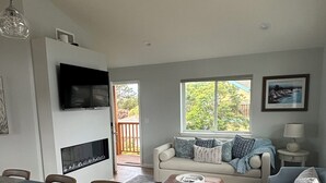 Un salon moderne comprenant un canapé, un pouf et un coin repas avec des chaises et une table.
