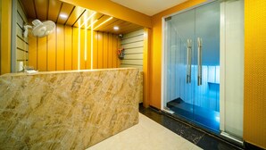Un área de recepción con mostrador de mármol, puerta de cristal y diseño interior moderno.