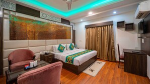 Una habitación de hotel con cama, escritorio, silla, sofá, ventilador de techo y aire acondicionado.
