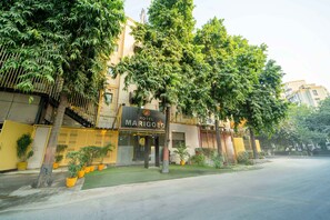 A hotel named Marigold with a modern facade, large windows, and a well-maintained lawn. - Treebo Marigold (New Delhi)