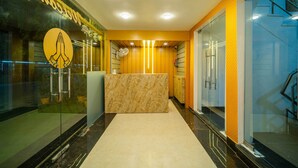 Un área de recepción con mostrador de mármol, paredes de vidrio y una pared de acento amarilla.