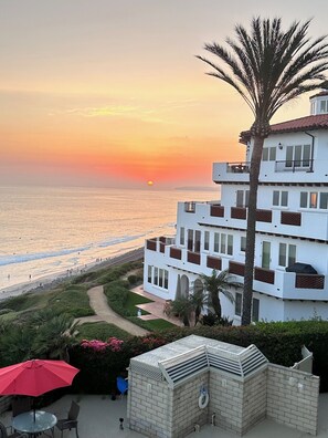 A multi-story building with balconies overlooking a beach at sunset. - Your oceanfront dream condo in beautiful San Clemente! (San Clemente)