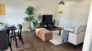 A modern living room with a dining area, a sofa, a TV, and potted plants. - Charming 2-bedroom duplex apartment with WiFi in charming Norwich (Norwich)