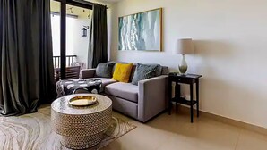 Un salon avec un canapé, une table basse, une lampe et un tableau au mur.