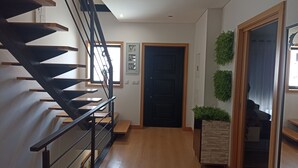 A staircase with a modern design, a wooden floor, a black door, and a small plant.