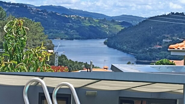 A swimming pool with metal ladders on a rooftop, overlooking a lake and hills.