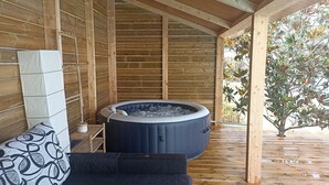 A wooden room with a hot tub, a sofa, and a table with a water heater.