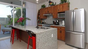 Una cocina moderna con encimeras de granito, electrodomésticos de acero inoxidable y armarios de madera.