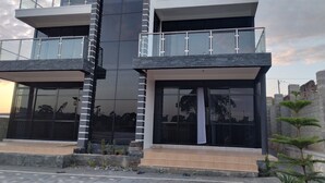A modern multi-story building with glass balconies and a central column. - Muguet by Ibiscot Development (Entebbe)