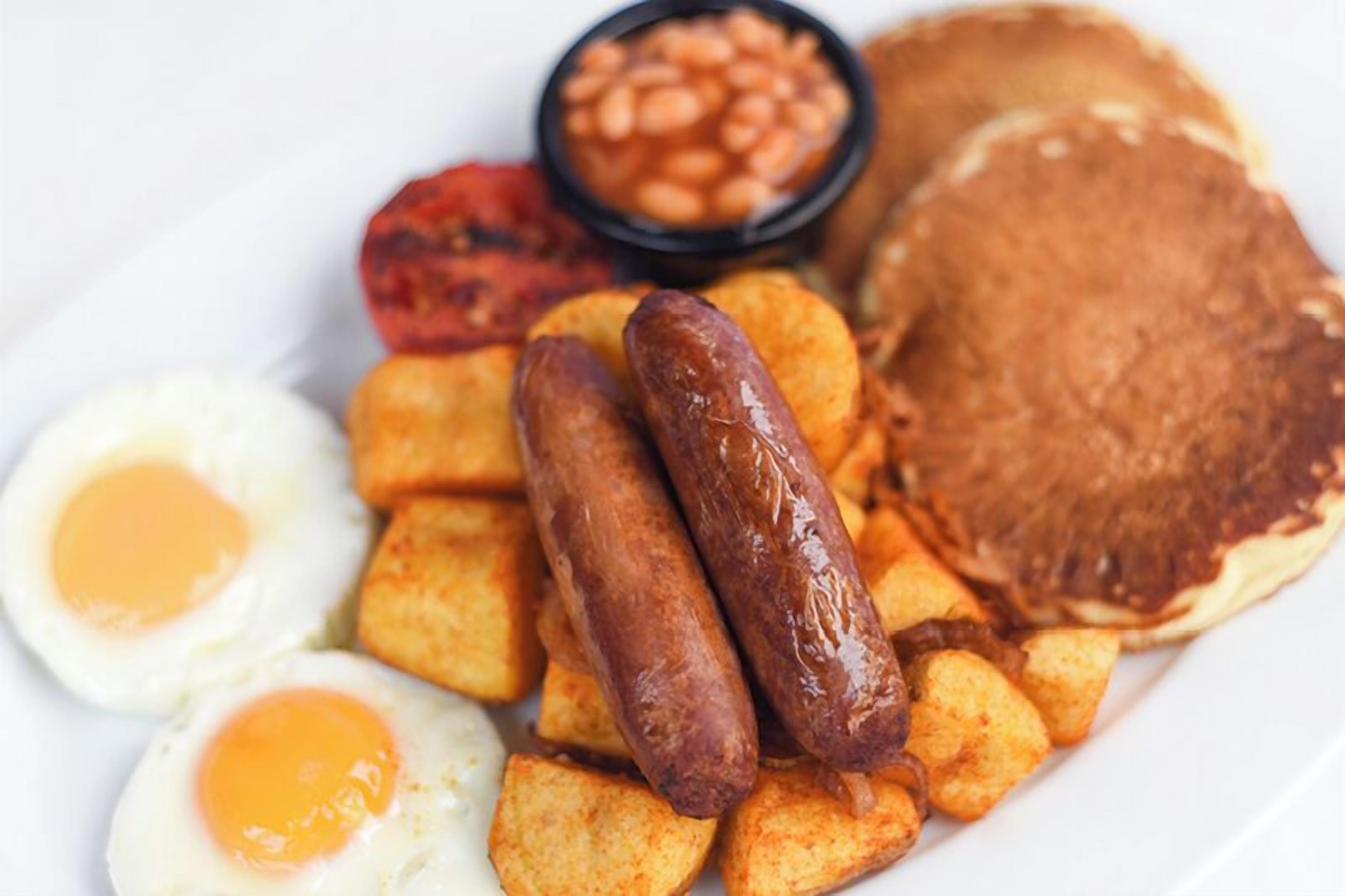 A plate of breakfast food including sausages, eggs, toast, and beans.