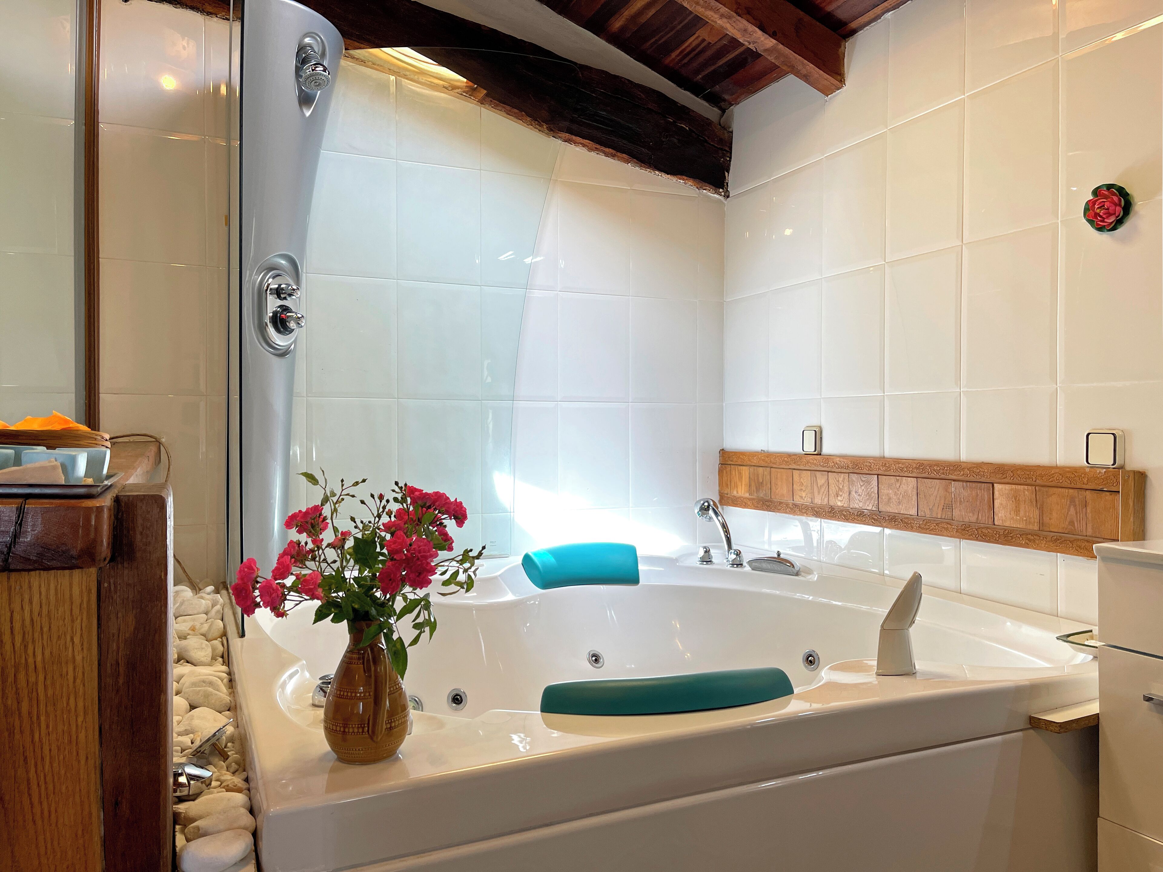 Un baño moderno con una bañera grande, un tocador de madera y un jarrón de flores.