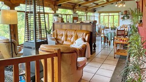 Una stanza accogliente e luminosa, con un divano in pelle, arredi in legno e un'area da pranzo con tavoli e sedie.
