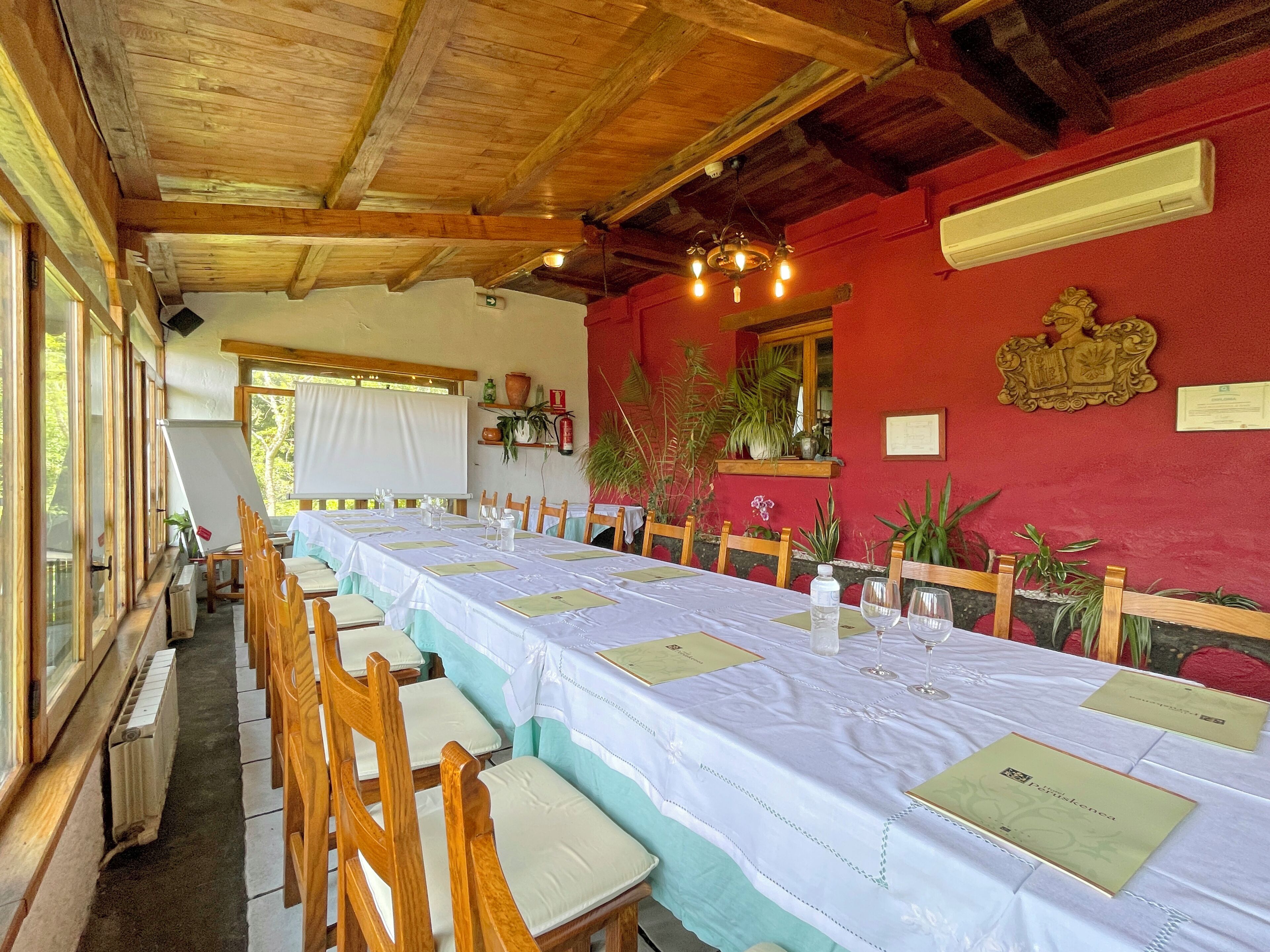 A long dining table with chairs, a whiteboard, and a red wall with decorations.
